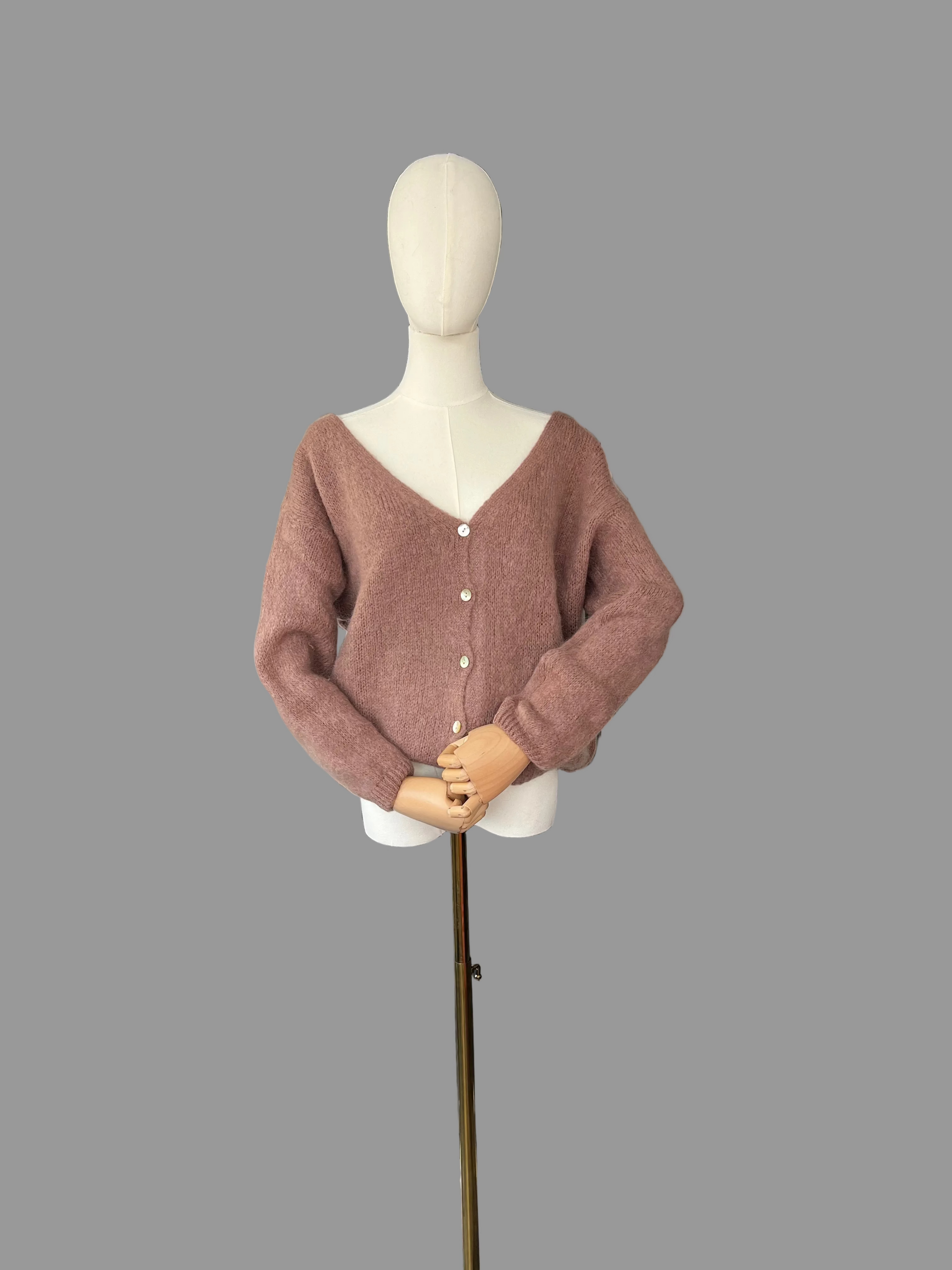Mannequin wearing a brown cardigan in a room with a radiator and shoes on the floor.